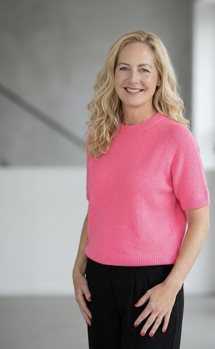 Anne Brenner lächelt im pinkfarbenen Pullover in einem hellen Raum