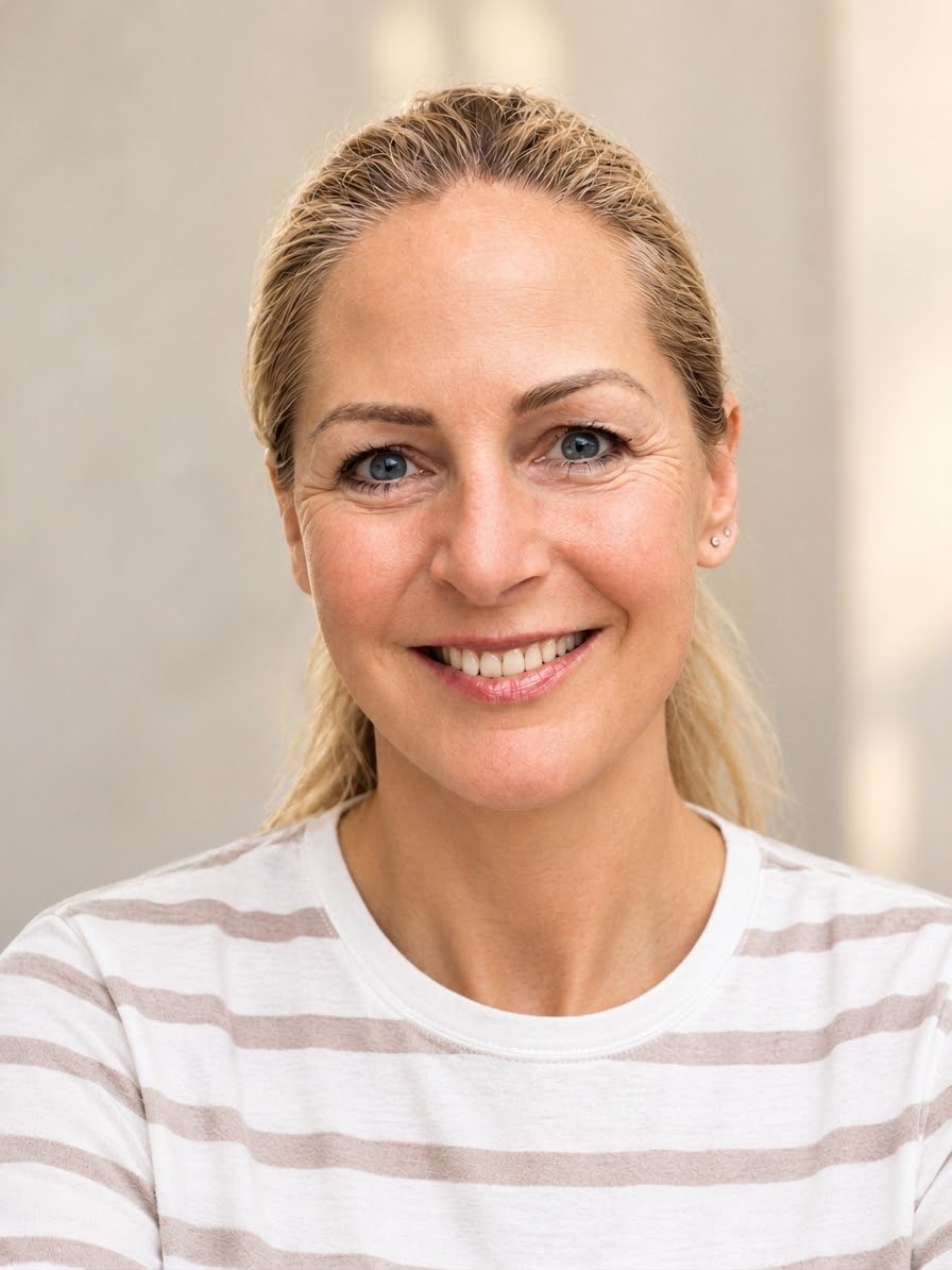 Anne Brenner lächelt offen in die Kamera, im gestreiften Shirt vor hellem Hintergrund